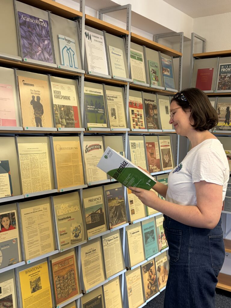 Eine Mitarbeiterin liest am Zeitschriftenregal der CIBEDO-Bibliothek in den CIBEDO-Beiträgen