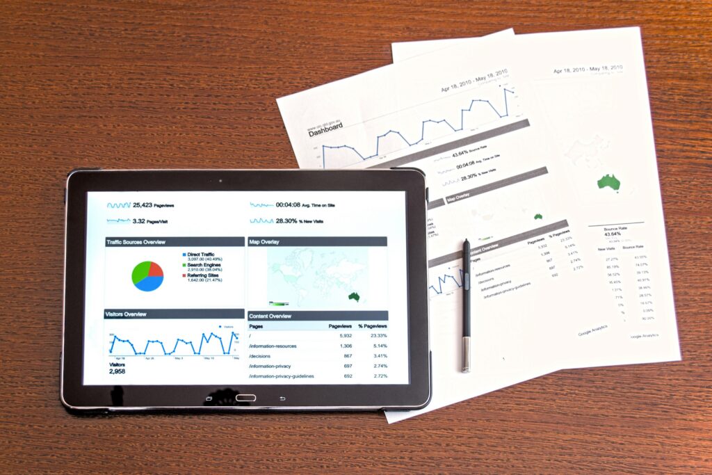 Tablet und Ausdrucke mit Diagrammen auf einem Holztisch