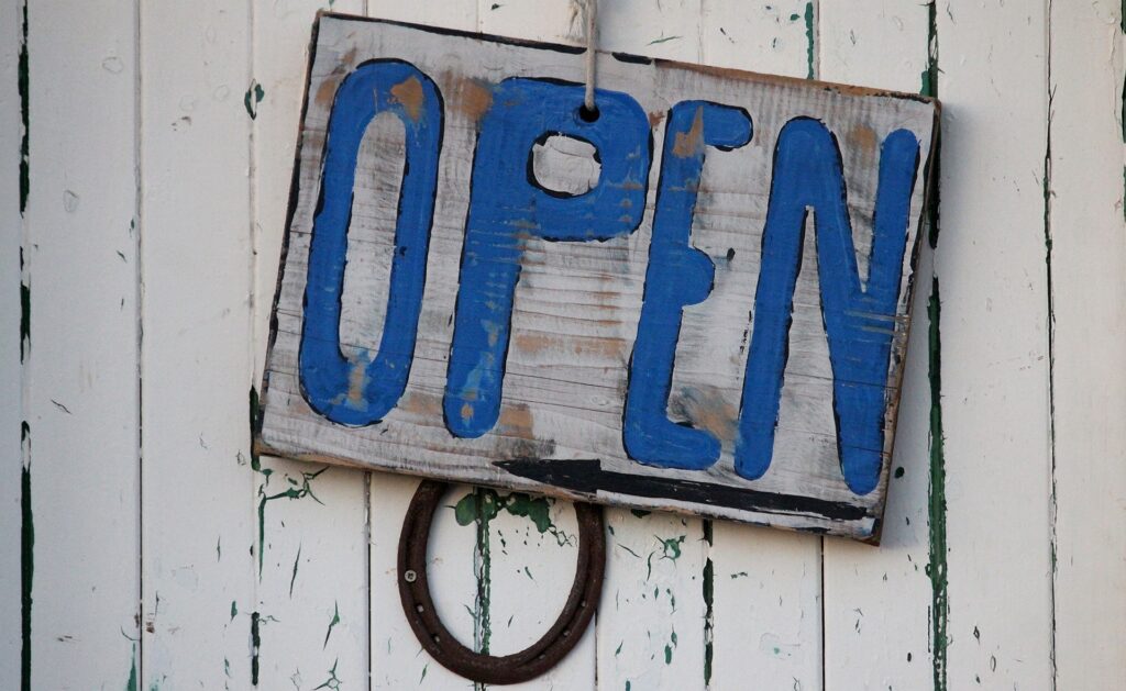 Handgemaltes Schild mit der Aufschrift „Open“ an einer Holztür